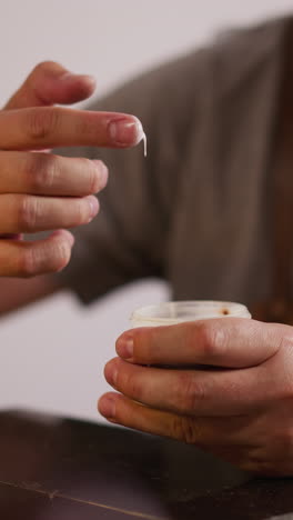 handyman takes glue for leathers from bottle with finger at workplace closeup. leathersmith prepares supplies for material processing in studio