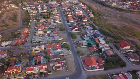 Inclinación-Aérea-Hacia-Arriba-Y-Panorámica-A-La-Derecha-Desde-Casas-Y-Automóviles-Hasta-El-Extremo-Sur-De-Aruba-Con-Hooiberg-En-El-Fondo