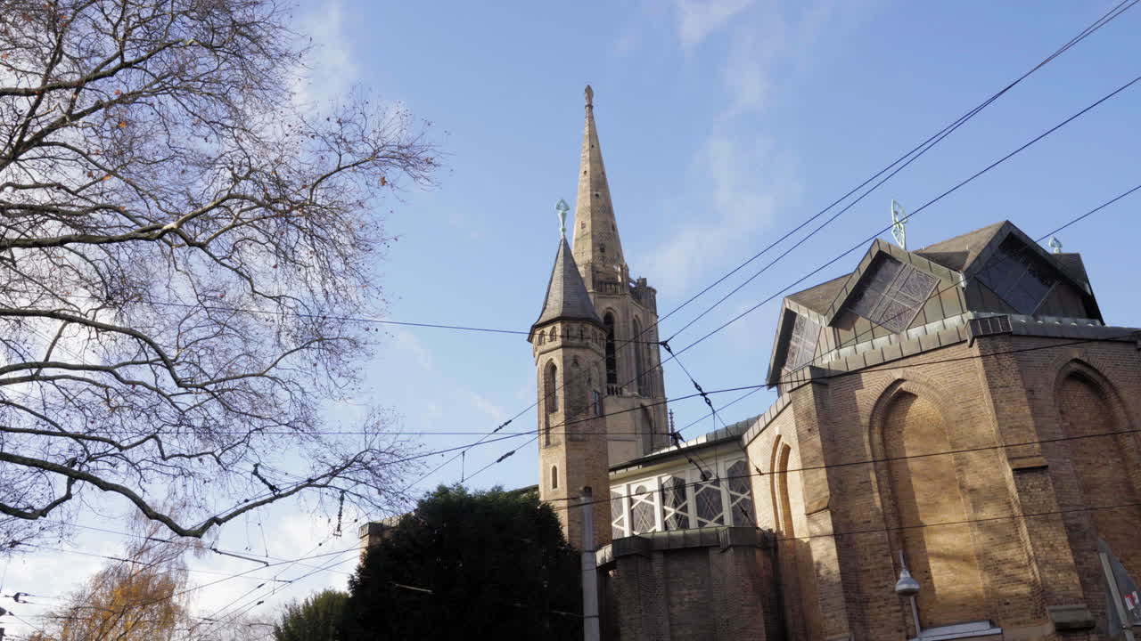 겨울 하늘을 배경으로 날카로운 첨탑을 가진 른의 고 양식의 교회. 벌거벗은 나무 가지와 상공 전선은 웅장한 건축물에 도시적인 감각을 더합니다.