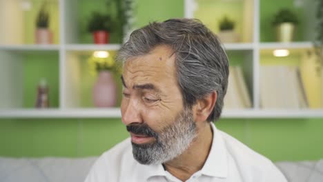 worried mature man looking at camera at home looking nervously.