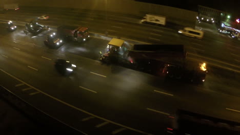 Flying-over-workers-laying-asphalt-at-night