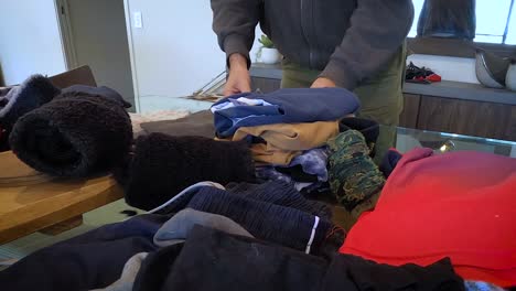 a casually dressed househusband folds and arranges clean washing