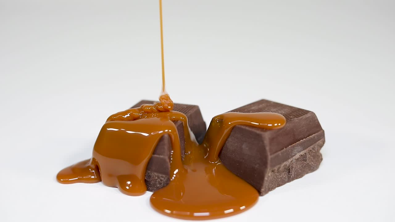 deliciosa salsa de caramelo lloviznando sobre fudge de chocolate con leche - fondo blanco