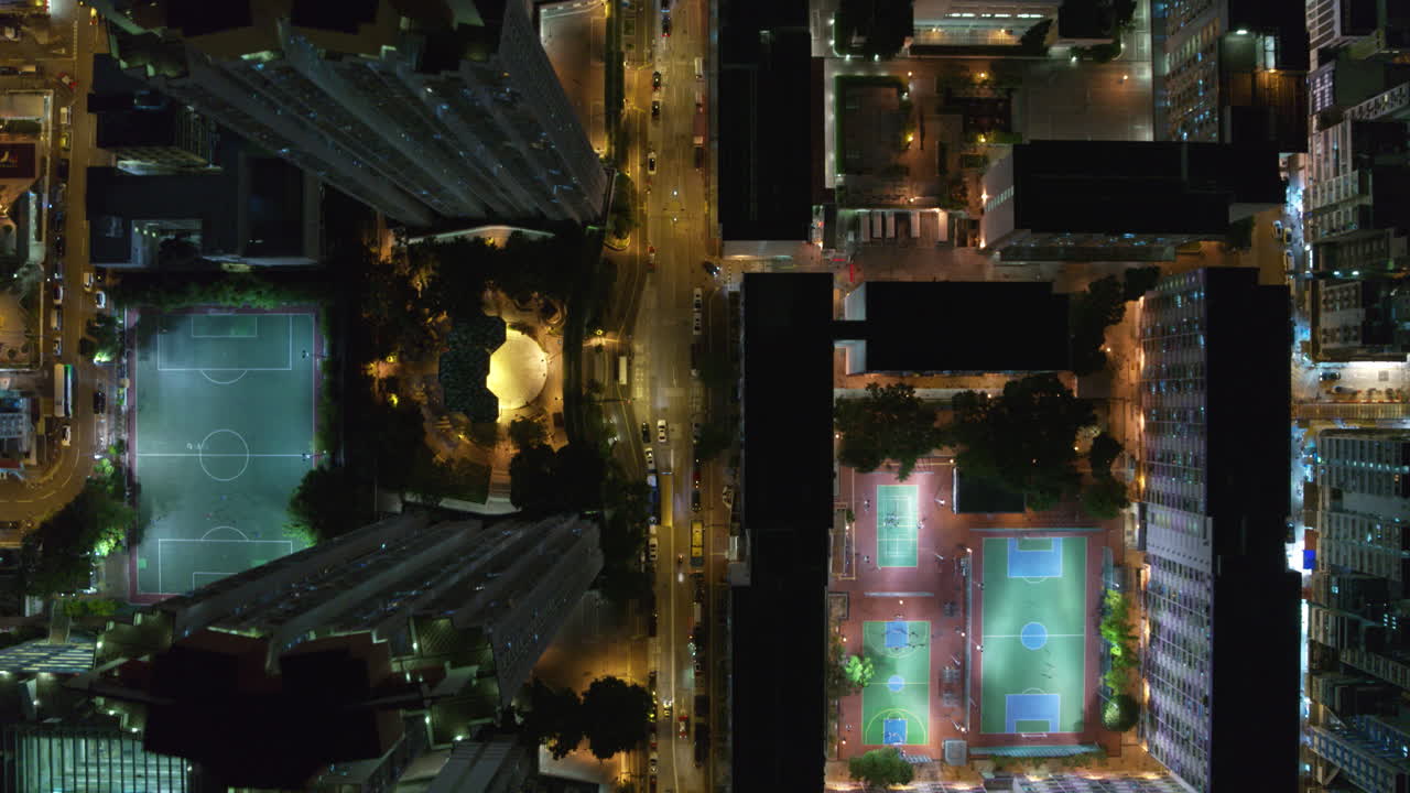 Drone top-down night view of city grid with bright streets, buildings, and traffic