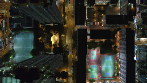 drone top-down night view of city grid with bright streets, buildings, and traffic