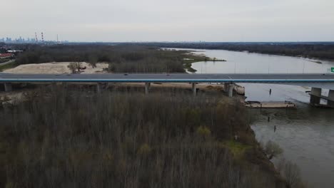 Aerial-flyover-new-build-modern-bridge-with-driving-vehicles-beside-Vistula-River-in-Poland