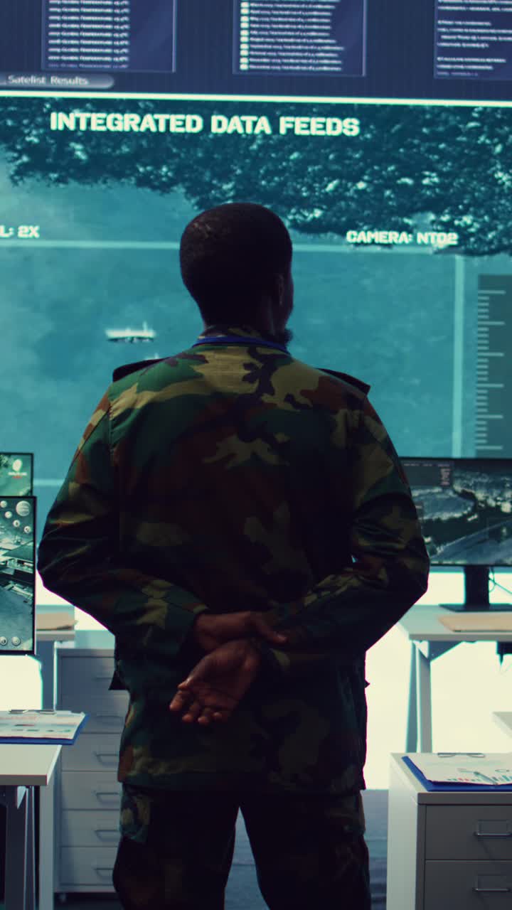 Man in Military Uniform Observing Integrated Data Feeds on Large Screen