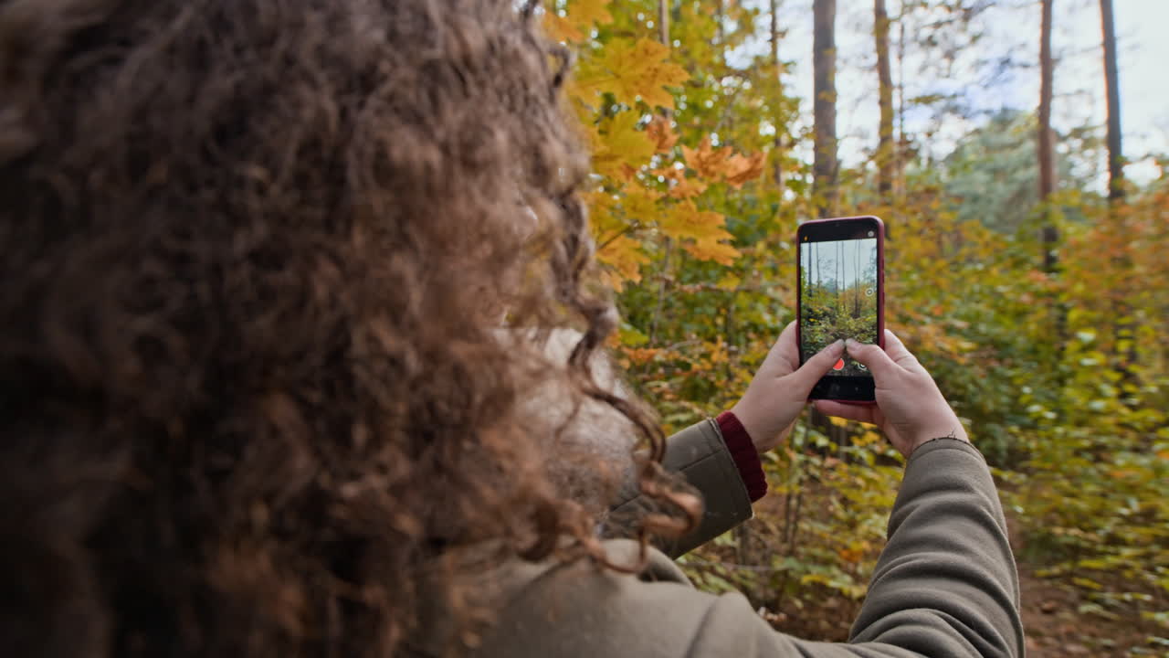 Woman taking pictures in the forest during autumn