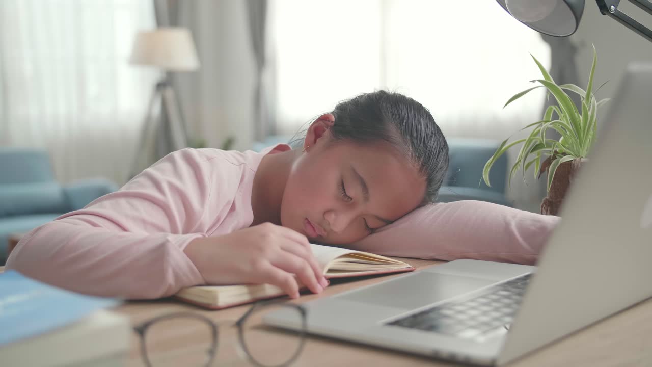 Tired Asia Girl Sleep On The Table At Living Room After Doing Home Work, Child Learning Online At Home
