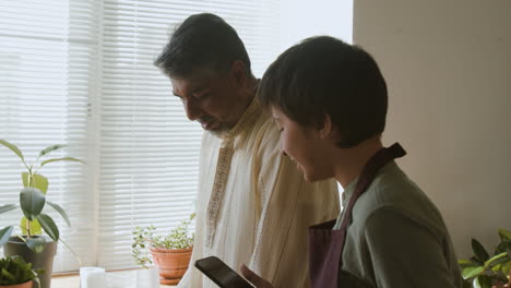 father and son cooking together in a kitchen using a smartphone