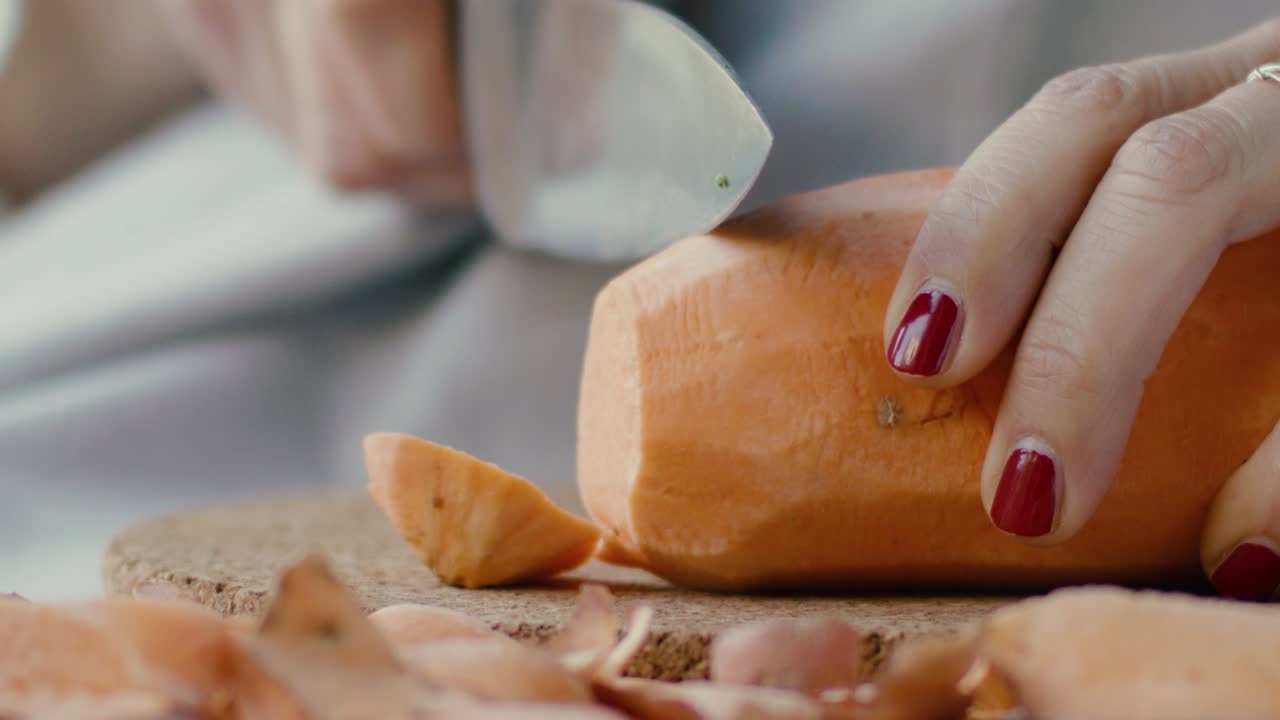 Detail of a hand cutting a whole sweet potato and turning it into pieces, in slow motion