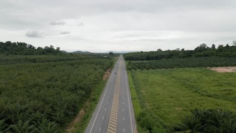 Aerial-view-of-highway-in-countryside-on-cloudy-day,-backwards-movement