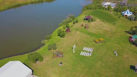 green field with wedding decorations at lake aerial view