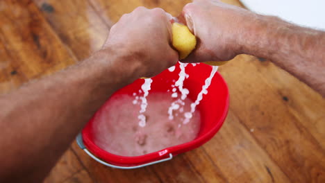 Close-Up-Of-Man-Squeezing-Water-Into-Bucket-After-Domestic-Leak