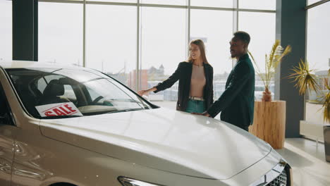 pareja mirando un coche para la venta en un concesionario