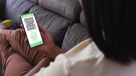 mujer en casa con un teléfono inteligente con certificado de vacunación contra la covid y código qr en la pantalla