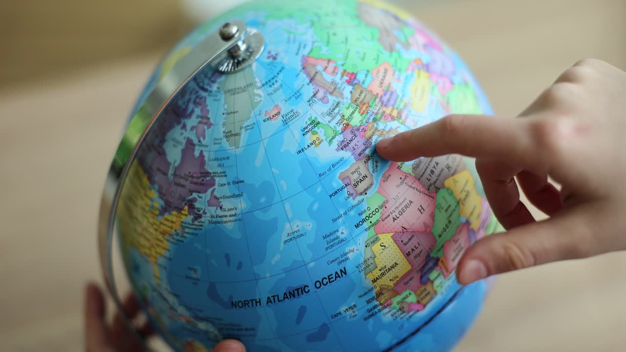 Image of a globe with a person pointing at Spain