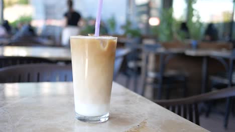 a glass of iced coffee on a table at a cafe