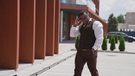 african american person in the city. serious businessman with black skinned body waiting for somebody near modern office center outdoors.