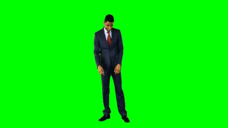 Tensed-businessman-standing-against-green-background