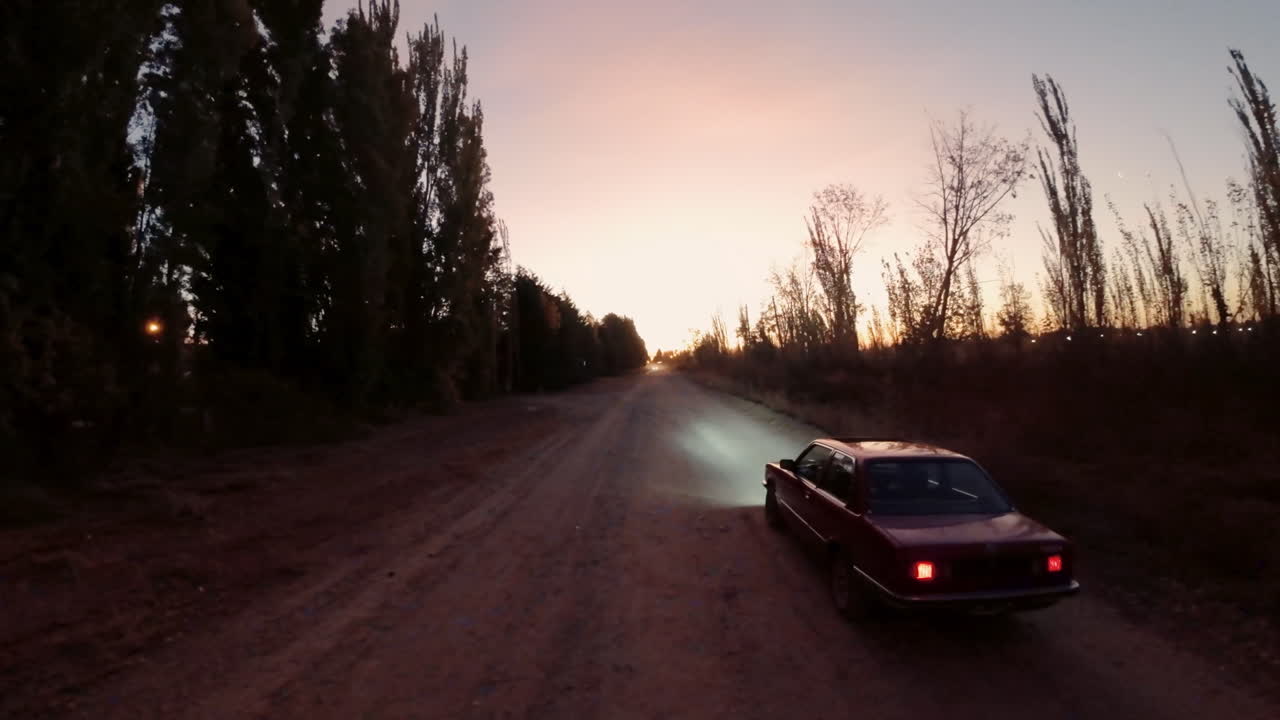 Auto rossa in corsa su una strada sterrata al tramonto