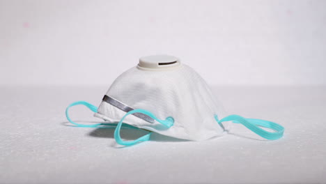 hand putting protective facial white mask mask against threat like corona covid-19 virus on white backing protecting mouth and nose on plate capture in 4k 60fps