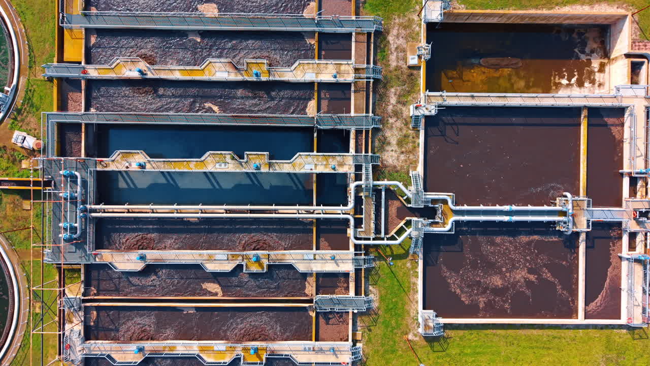 Symmetrical top view of rectangular aeration tanks in water facility. Overhead perspective of industrial water purification system with metal walkways and pipes