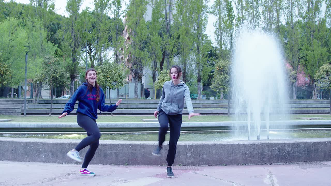girls jump from the edge of a fountain and perform a synchronized dance