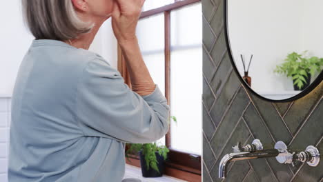 applying skincare, senior woman in bathroom focusing on self-care routine, at home