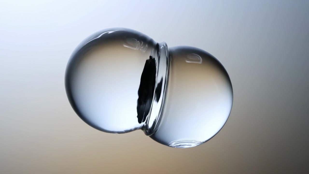 Sequential close-up study showing two suspended glass droplets that approach, contact, merge, and settle over clip timeline