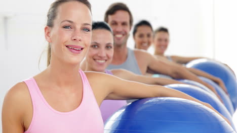 Fitness-class-holding-exercise-balls-smiling-at-camera