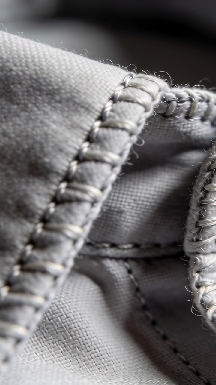 Vertical video: Shifting camera inspecting braid and reinforced seam on hoodie, showing eyelet