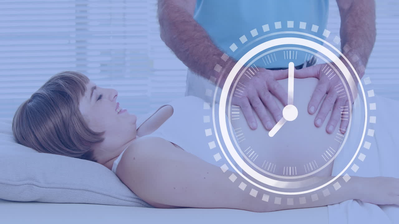 행복한 임신한 백인 여성이 남편에 의해 배를 마사지하고 있습니다.