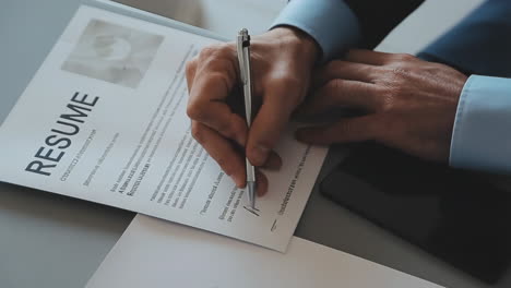 person writing on a resume document with a pen