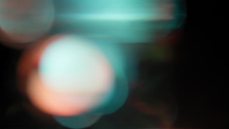 orange and teal color light flashing leaks on black bokeh