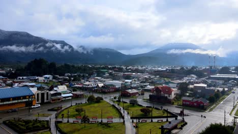 aerial view dolly in from the main square of hornopiren, chile, hornopiren volcano in the background covered by clouds