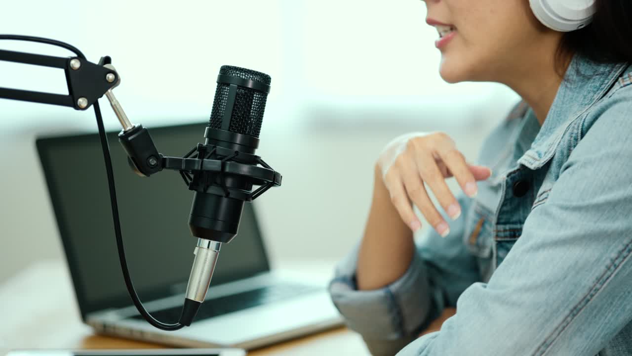 micrófono de condensador de primer plano del creador de contenido mujer anfitriona transmitiendo su podcast en portátil con auriculares conversación de entrevista en el estudio de transmisión en casa. blogger grabando voz por radio.