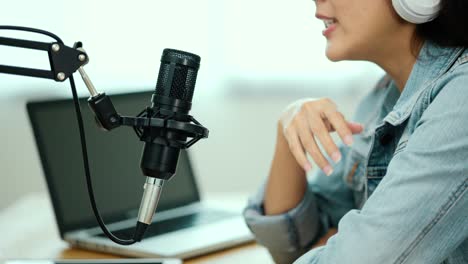 close-up condenser microphone of content creator woman host streaming his a podcast on laptop with headphones interview conversation at home broadcast studio. blogger recording voice over radio.