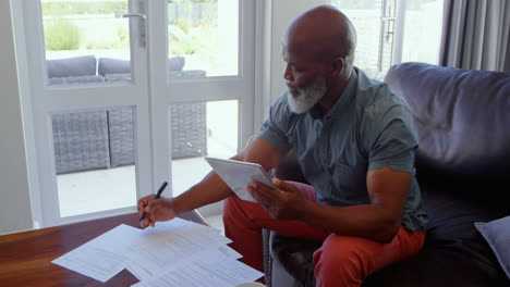 side view of mature man signing documents in living room at home 4k