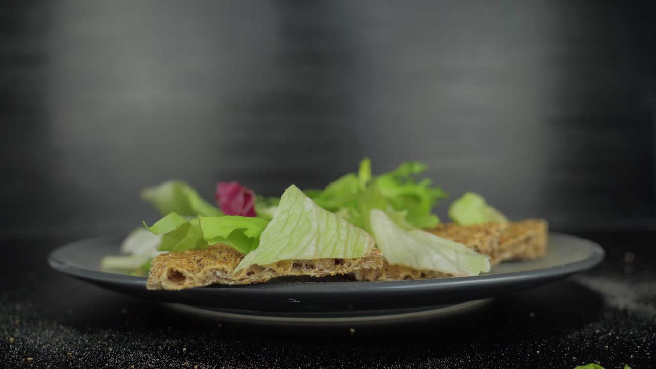 크리스브레드에 떨어지는 그린 샐러드 잎, 회색 배경 클로즈업