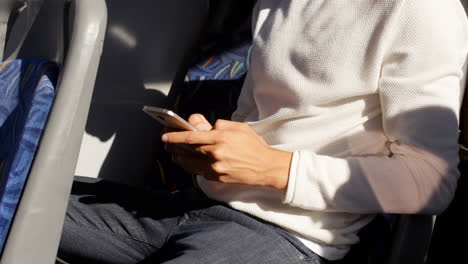 man seated on a bus texting