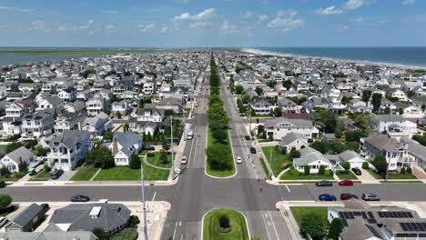 stone harbor, new jersey. luxury beach houses with solar panels, tree-lined roads, atlantic ocean and classic american coastal town symmetry under blue summer sky. aerial wide shot