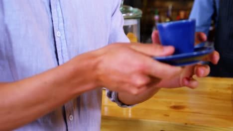 sección media del camarero que sirve café al cliente masculino en el mostrador