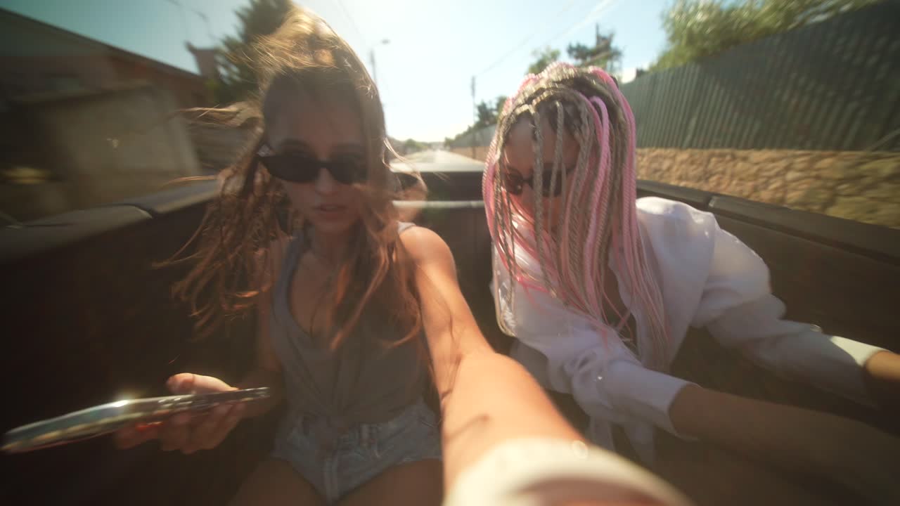 Amici che si godono un viaggio on the road soleggiato in una decappottabile.