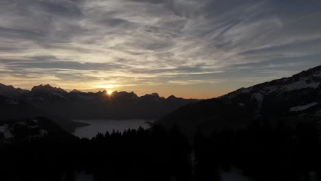 sunrise over the snowy amden mountains, casting golden light on peaks, aerial view