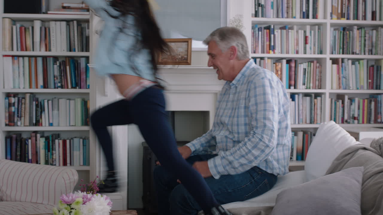 happy little girl hugging grandfather playfully jumping into grandad's arms having fun enjoying weekend with grandparent at home