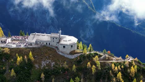 un edificio de piedra rústica con un techo desgastado se sienta en medio de la vegetación exuberante en la cima de una montaña