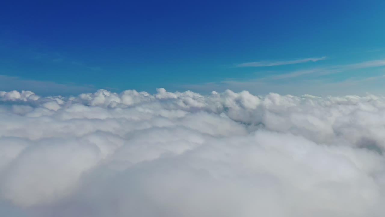 Blue sky and white clouds background. Stunning footage above clouds with blue sky. Travelling by air background. Real time footage. Aerial view.