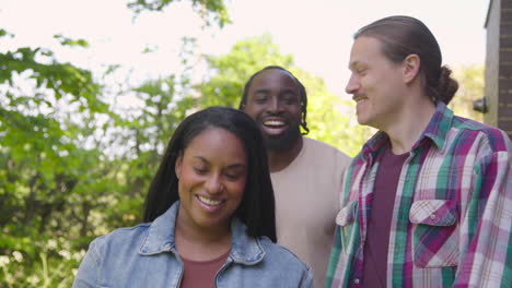 outdoor shot of multi-cultural group of friends holding bottle of wine arriving for party celebration