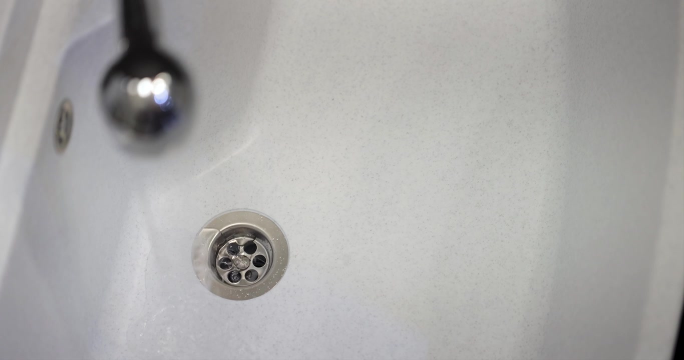 Water pouring from a faucet into a gray plastic sink, 4K